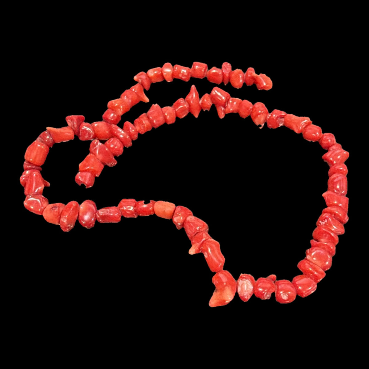 Red bamboo coral chip beads, 5-9x6-7mm, 17-inch strand, on a black background